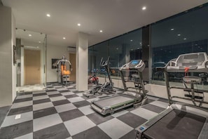 A gym with treadmills, stationary bikes, and a mirrored wall. - Hotel BL (Hyderabad)