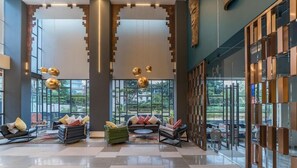 Un vestíbulo amplio con techo alto, ventanas grandes y mobiliario moderno.