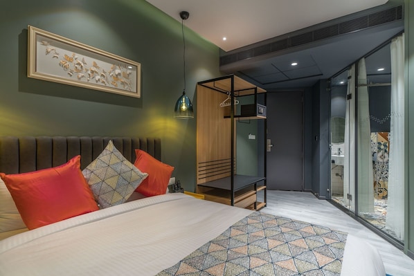 A modern hotel room with a bed, a wooden wardrobe, a walk-in closet, and a bathroom with a glass shower. - Hotel BL (Hyderabad)