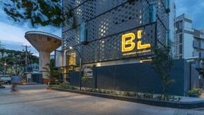 A modern building with a prominent 'BL' sign, featuring a unique perforated facade and a large, cylindrical structure nearby.