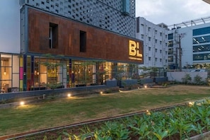 A modern building with a prominent 'BL' sign, large windows, and a well-maintained lawn. - Hotel BL (Hyderabad)