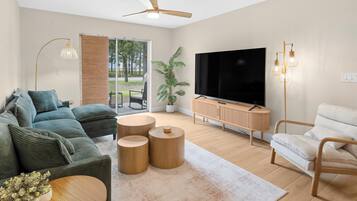 A modern living room with a sofa, a TV, a coffee table, and a plant.