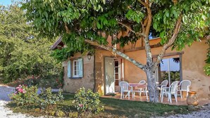 Un edificio rústico con un patio, mesas al aire libre y un árbol.