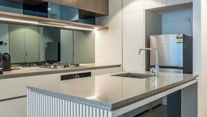 A modern kitchen with a built-in stove, a sink, and a stainless steel refrigerator. - Resort-Style CBD 1-Bedroom Stay Walk to Everything (Brisbane City)