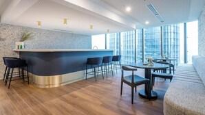 A modern bar area with a curved counter, bar stools, and a dining table with chairs. - Resort-Style CBD 1-Bedroom Stay Walk to Everything (Brisbane City)