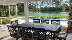 An outdoor patio with a table and chairs, a view of a lake, and a palm tree. - Dreamin O'Sprey! Amazing View & Plenty O'Privacy! (Clermont)