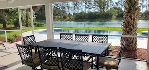 An outdoor patio with a table and chairs, a view of a lake, and a palm tree. - Dreamin O'Sprey! Amazing View & Plenty O'Privacy! (Clermont)