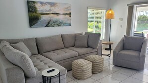 A living room with a grey sofa, a grey armchair, a small round table, and a woven ottoman. - Dreamin O'Sprey! Amazing View & Plenty O'Privacy! (Clermont)