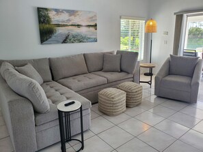 A living room with a grey sofa, a grey armchair, a small round table, and a woven ottoman. - Dreamin O'Sprey! Amazing View & Plenty O'Privacy! (Clermont)