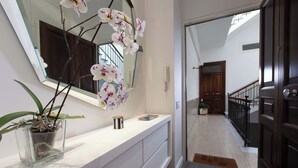 A hallway with a white vanity, a potted orchid, a mirror, and a dark wooden door. - Terrazza Di Sorrento, Town Centre Apartment (Sorrento)