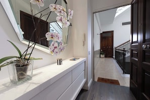 A hallway with a white vanity, a potted orchid, a mirror, and a dark wooden door. - Terrazza Di Sorrento, Town Centre Apartment (Sorrento)