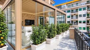 A modern building with large glass windows, a stone facade, and a balcony with potted plants. - Terrazza Di Sorrento, Town Centre Apartment (Sorrento)