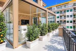 A modern building with large glass windows, a stone facade, and a balcony with potted plants. - Terrazza Di Sorrento, Town Centre Apartment (Sorrento)