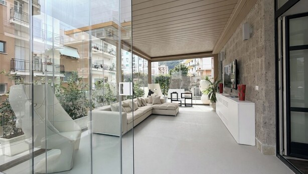 A modern living room with a sectional sofa, a glass partition, and a view of the cityscape. - Terrazza Di Sorrento, Town Centre Apartment (Sorrento)