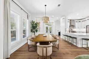 Eine moderne Küche mit weißen Schränken, einem Holztisch und Barhocker.