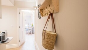 Ein Flur mit einem hölzernen Kleiderständer, einer gewebten Tasche und einer Kaffeemaschine.