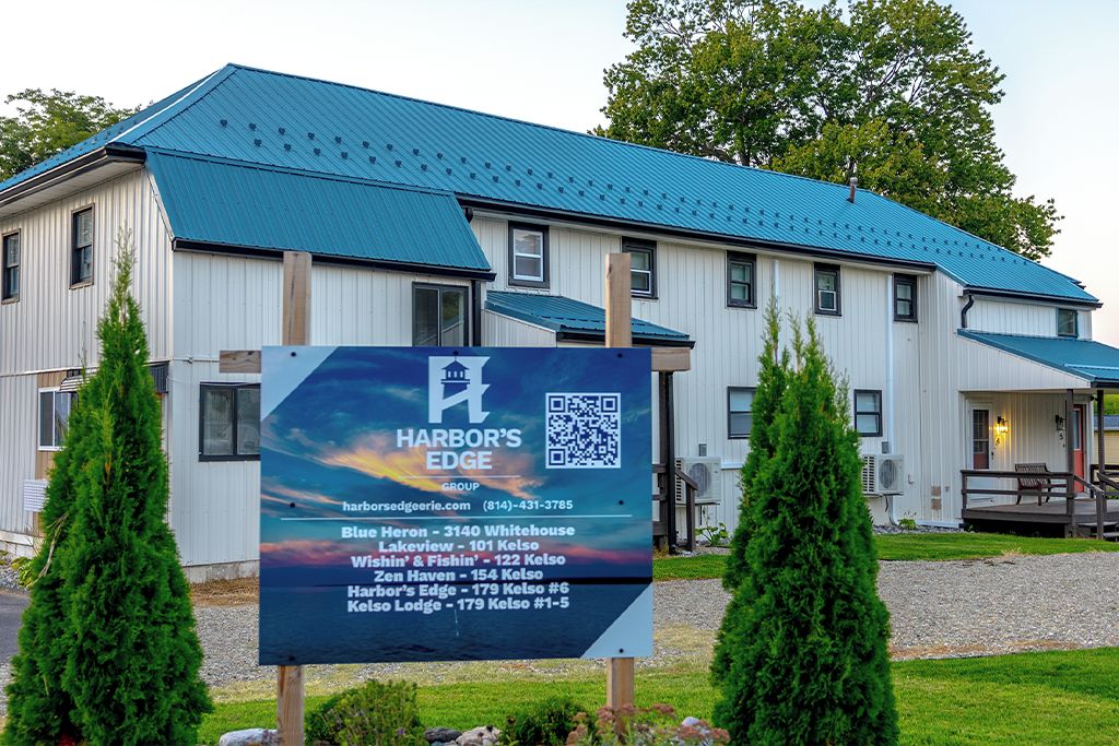 A large building with a blue roof, a signboard for Harbor's Edge Group, and a QR code.