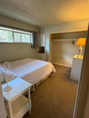 A bedroom with a bed, bedside table, lamp, closet, and a window. - CYC0605 - Herbert Hideaway (South Lake Tahoe)