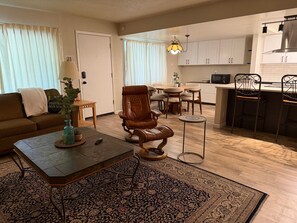 Una sala de estar con sofá, una mesa de centro, un tapete y un comedor con sillas y una mesa.