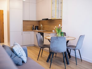 Eine moderne Küche mit weißen Schränken, einer Holz Arbeitsplatte und einem Essbereich mit einem runden Tisch und grauen Stühlen.