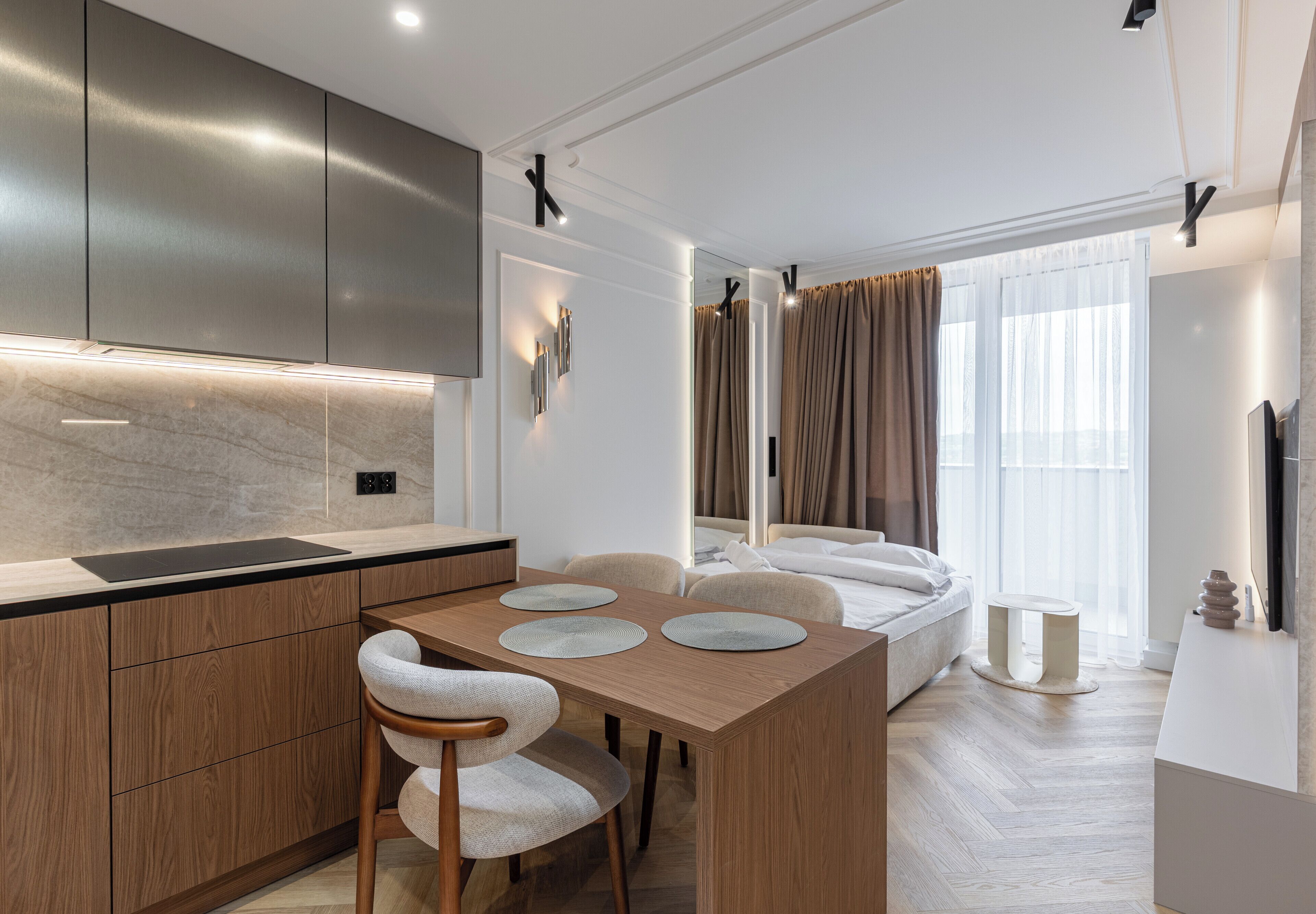 Una cocina moderna con armarios de madera, una mesa de comedor con sillas y un ventanal con cortinas.
