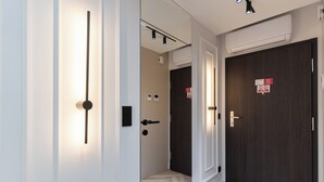 A hallway with a light fixture, a door with a sign, and an air conditioning unit. - Rzeszów Superior Apartment (Rzeszów)
