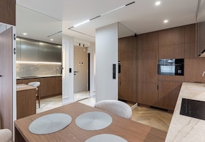 Una cocina moderna con armarios de madera, un microondas integrado y un comedor con mesa y sillas de madera.