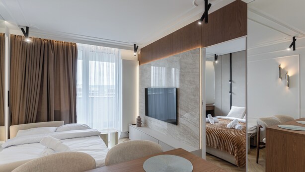 A modern hotel room with a large bed, a desk, a TV, and a dining area. - Rzeszów Superior Apartment (Rzeszów)