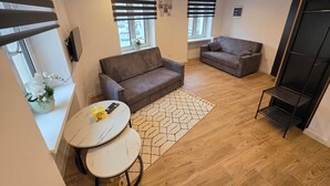 Una sala de estar moderna con dos sofás, una mesita redonda y un estante negro.