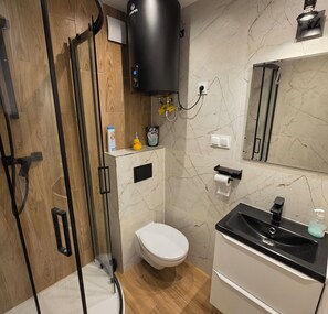 A modern bathroom with a shower, toilet, and sink.