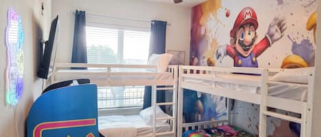 Una habitación infantil con literas, un ventilador de techo y un mural de Mario.
