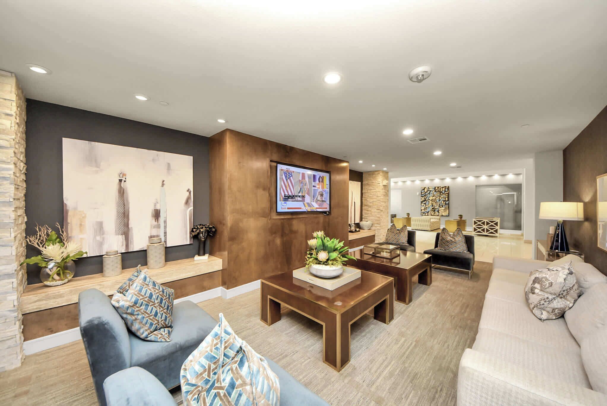 A modern living room with a sofa, armchair, coffee table, and a flat-screen TV mounted on the wall.