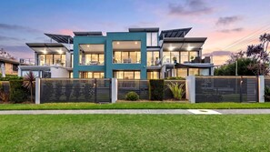 A modern two-story house with a flat roof, large windows, and a well-maintained lawn. - Bruma on Bowen - Opposite Shark Net Beach (Huskisson)