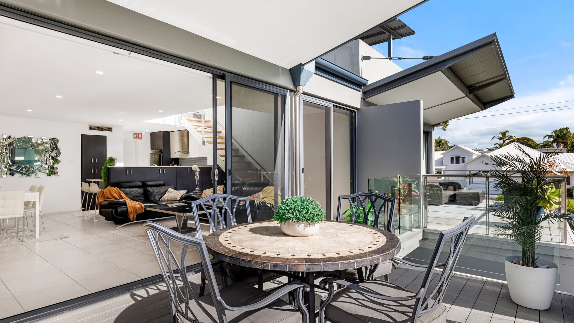 A modern living space with a dining area, a sofa set, and a potted plant.