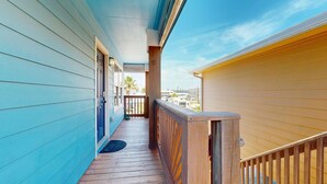 A wooden deck with a railing, a door, and a view of a residential area. - Shared Pool, Pet Friendly (Port Aransas)