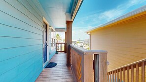 A wooden deck with a railing, a door, and a view of a residential area. - Shared Pool, Pet Friendly (Port Aransas)