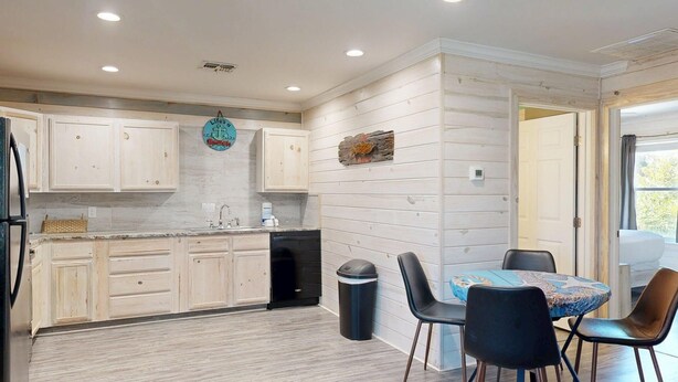 A modern kitchen with wooden cabinets, a sink, and a dining area with a table and chairs. - Shared Pool, Pet Friendly (Port Aransas)