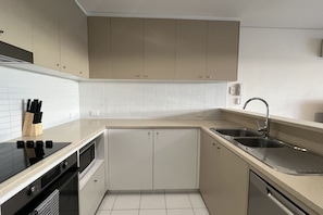 A modern kitchen with a black stove, a sink, and a dishwasher. - The Beating Heart of Gungahlin (Canberra)
