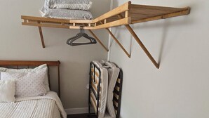 Ein Schlafzimmer mit einem Bett, einem Kleiderständer aus Holz und einem Koffer.
