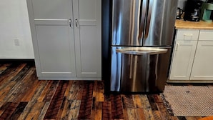 Eine Küche mit einem Edelstahl-Kühlschrank, Doppeltüren und Holzboden.