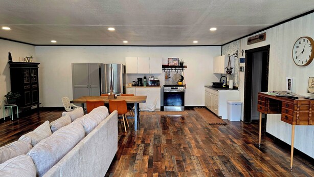 Eine moderne Küche mit Essbereich, Holzboden und einem Wohnzimmer mit Sofa.