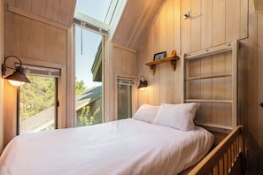 Ein Schlafzimmer mit einem Bett, einem Fenster und einer Holzwand.