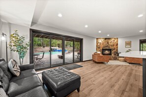 A modern living room with a fireplace, a pool view, and a cozy seating area. - Park City Red Pine Mountain Haus – 4BR/4BA, Pool & Hot Tubs (Park City)