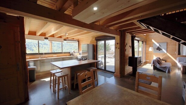A wooden interior with a kitchen, dining area, and a fireplace. - Le grand gîte de Combes (BESSE ET SAINT ANASTAISE)