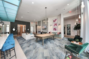 A spacious room with a pool table, bar area, and seating.