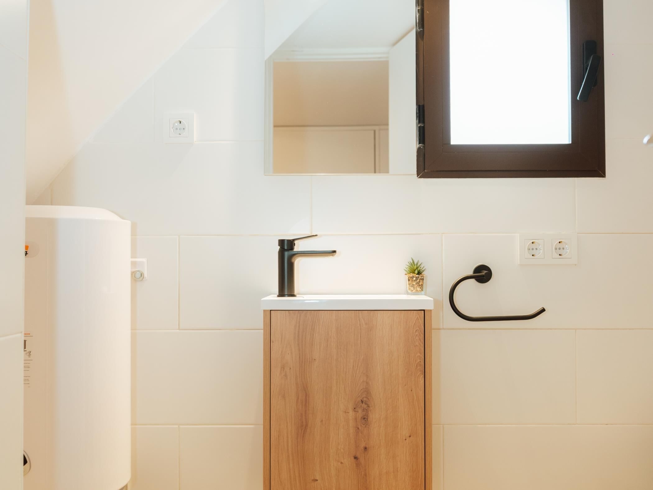 A bathroom with a wooden cabinet, a white sink, a mirror, and a towel rack.