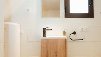 A bathroom with a wooden cabinet, a white sink, a mirror, and a towel rack.