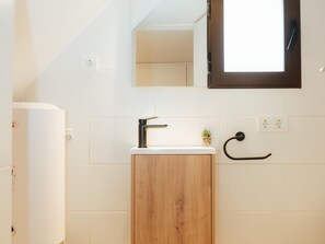 Une salle de bain avec un meuble en bois, un lavabo blanc, un miroir et un porte-serviettes.