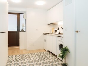 Una cocina funcional con lavadora, una pequeña encimera y un suelo estampado.