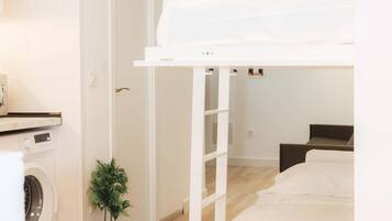 A room with a bunk bed, a washing machine, a small potted plant, and a checkered floor.